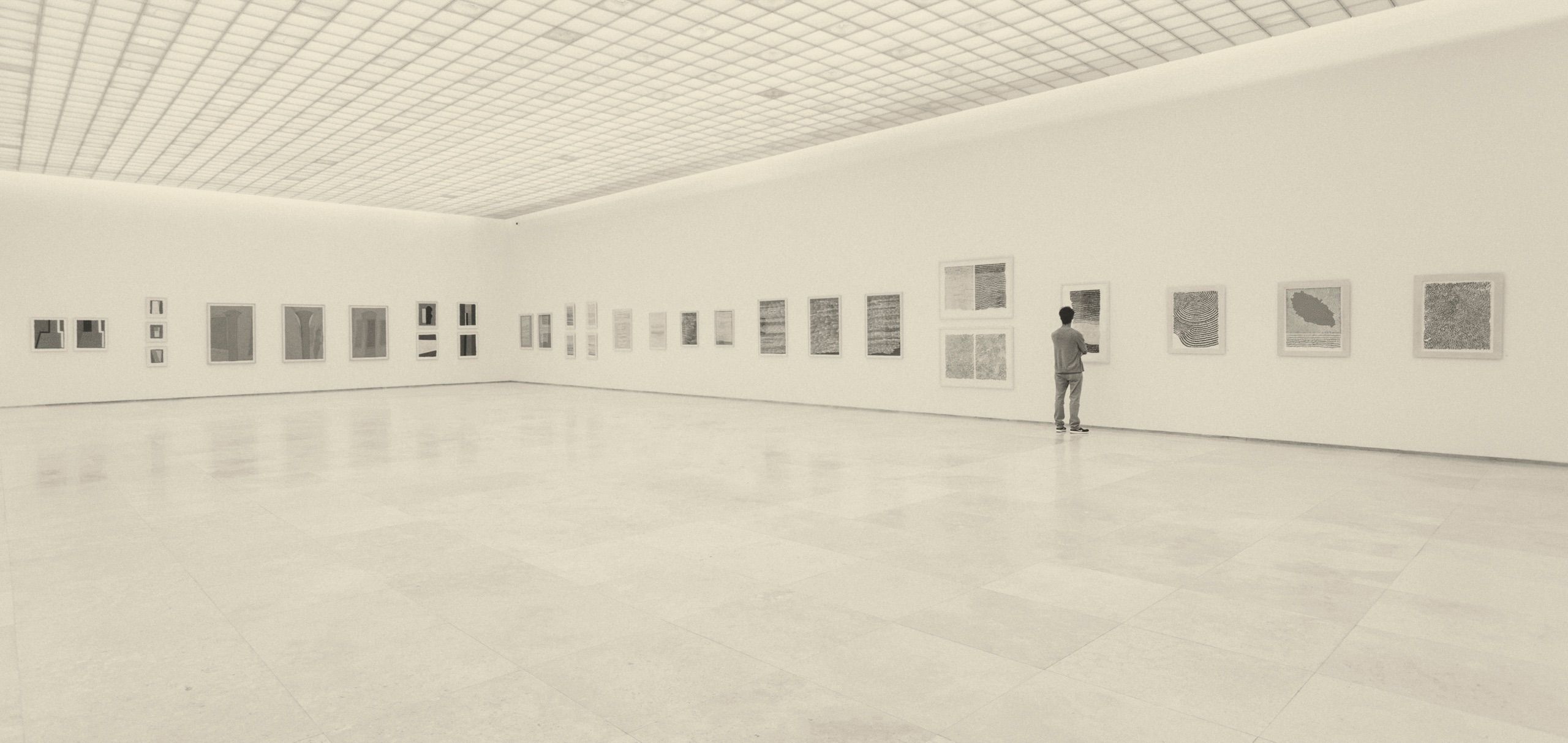 Framed works hung along the walls of a gallery